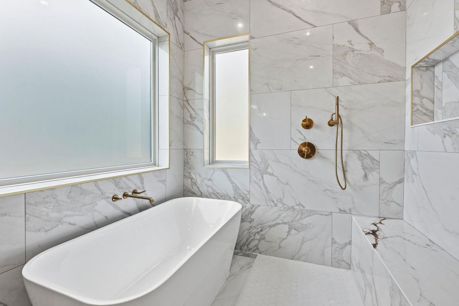 Floor-to-ceiling tile surrounds a sleek soaking tub and a modern walk-in shower.