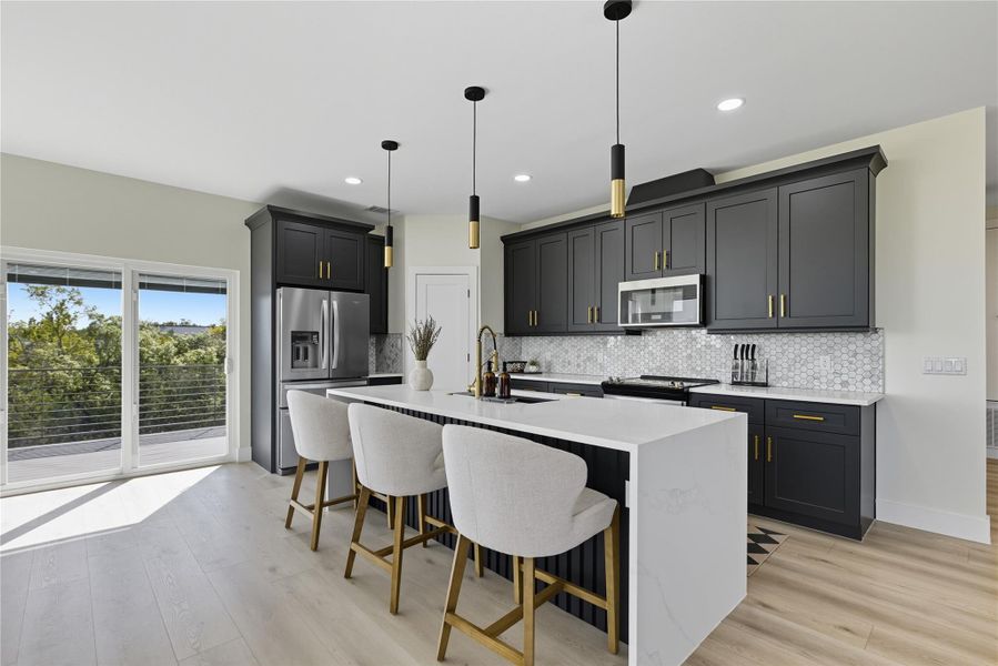 Kitchen featuring a kitchen breakfast bar, light stone counters, appliances with stainless steel finishes, light wood finished floors, and recessed lighting