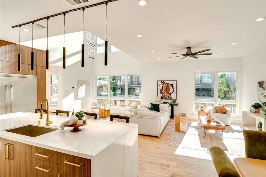 Kitchen featuring light stone countertops, sink, light wood-type flooring, hanging light fixtures, and ceiling fan