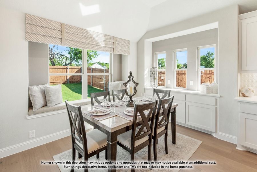Dining area with dark wood table, window seat, vaulted ceiling, and large windows overlooking backyard