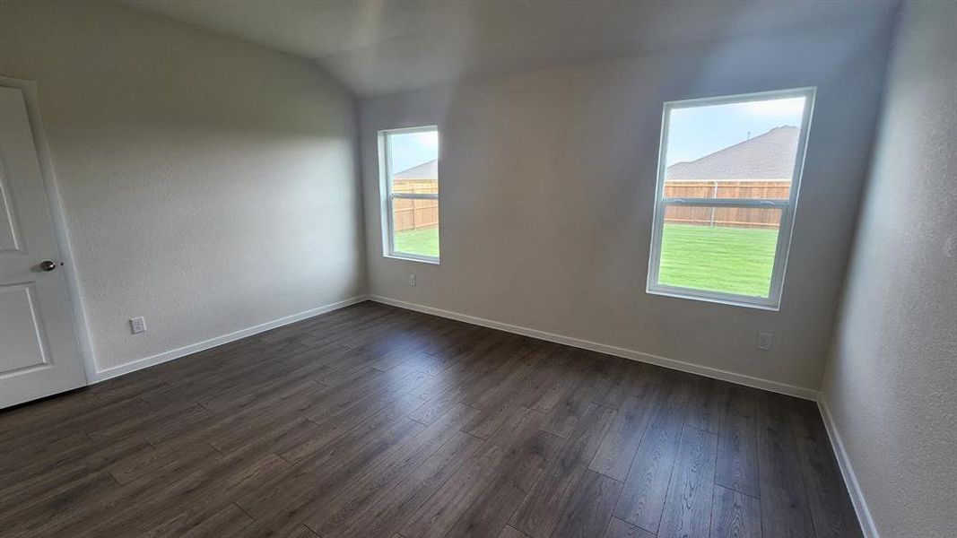 Room featuring wood-finish flooring, white baseboards, and neutral wall tones Room featuring wood-finish flooring, white baseboards, and neutral wall tones