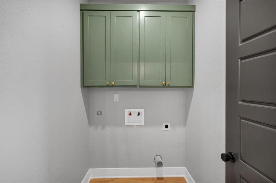 Laundry room with hookup for a washing machine, electric dryer hookup, cabinet space, and light wood-style floors Laundry room with hookup for a washing machine, electric dryer hookup, cabinet space, and light wood-style floors
