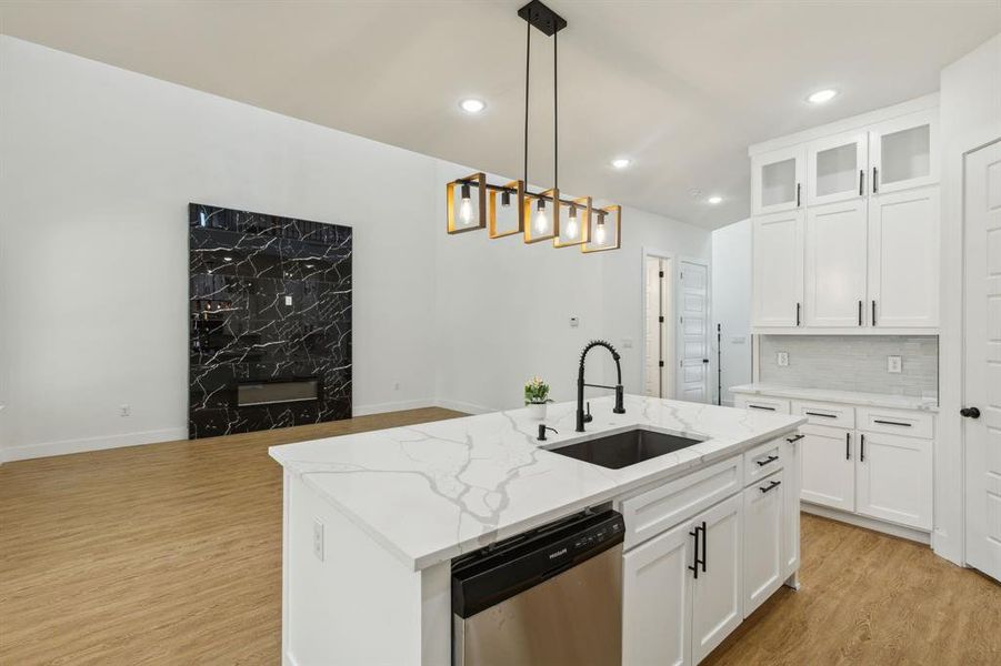 Kitchen featuring an island with sink, sink, light wood-type flooring, and stainless steel dishwasher