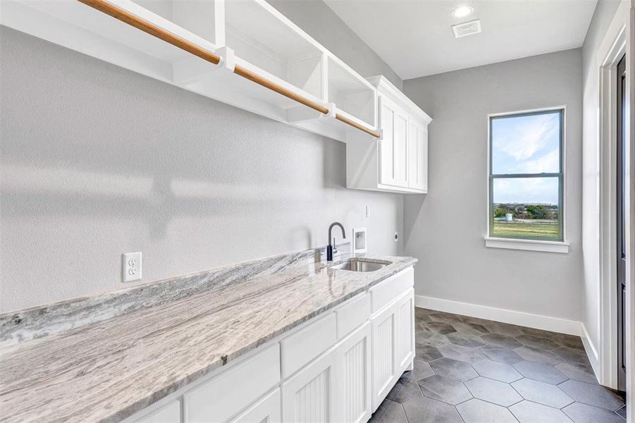 Laundry area with electric dryer hookup, cabinets, sink, washer hookup, and dark tile patterned floors