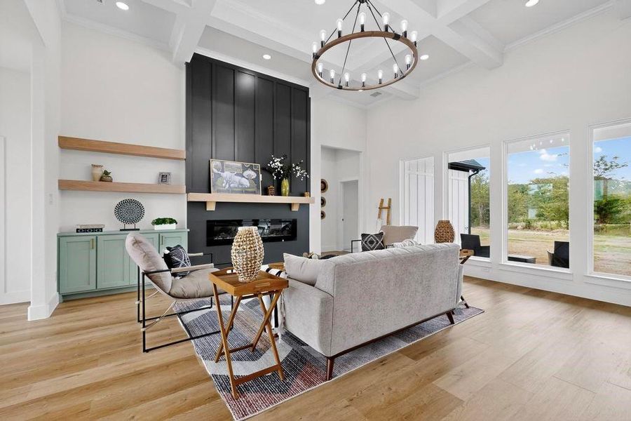 Living area featuring beam ceiling, a towering ceiling, light wood-style flooring, recessed lighting, and a chandelier Living area featuring beam ceiling, a towering ceiling, light wood-style flooring, recessed lighting, and a chandelier