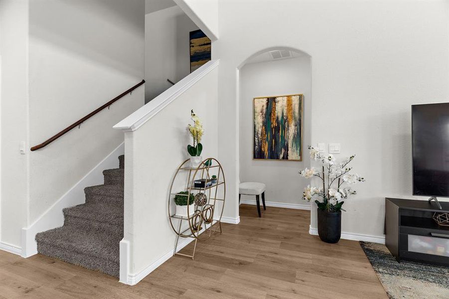 Stairway with arched walkways, baseboards, visible vents, and wood finished floors