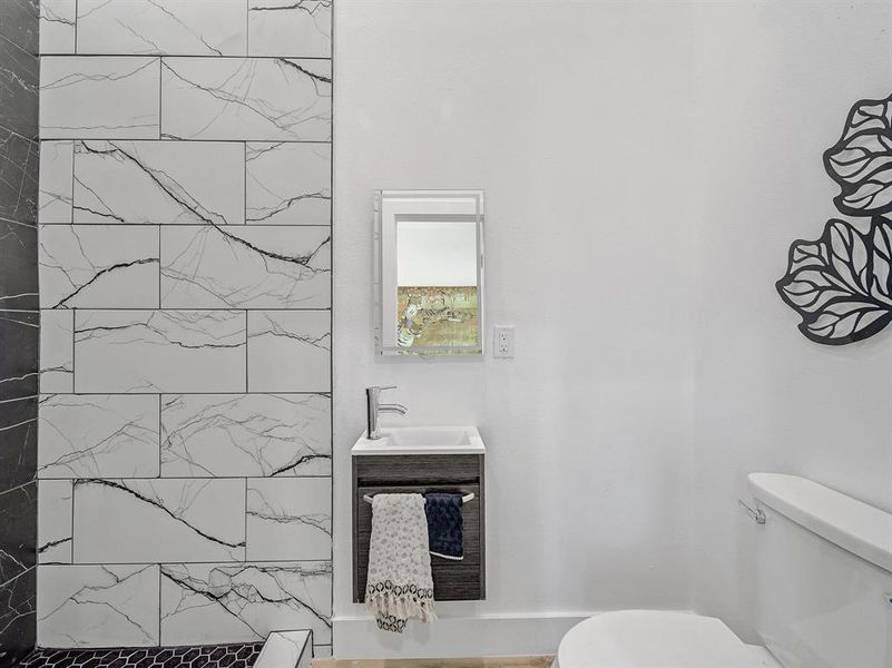 Bathroom featuring toilet, a tile shower, and vanity