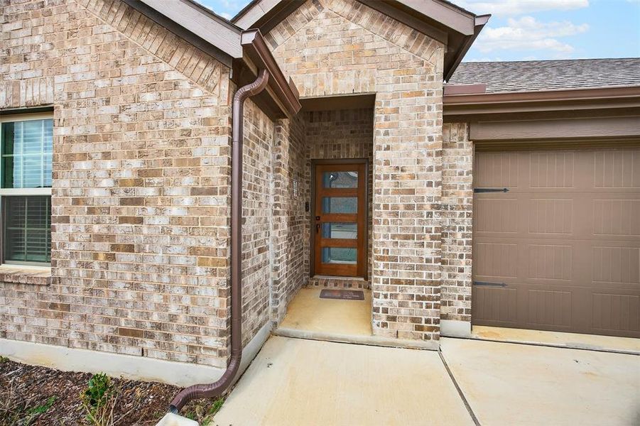 View of exterior entry featuring brick siding and a garage