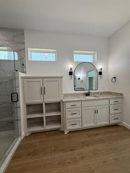 Bathroom featuring a marble finish shower, vanity, and plenty of natural light