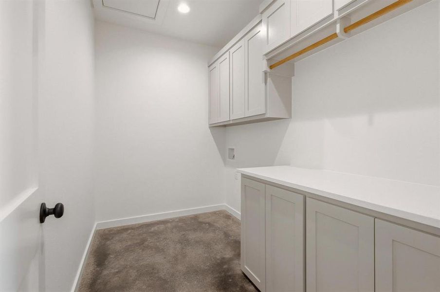 Utility room featuring white shaker-style cabinetry, a built-in hanging rod, and a spacious countertop