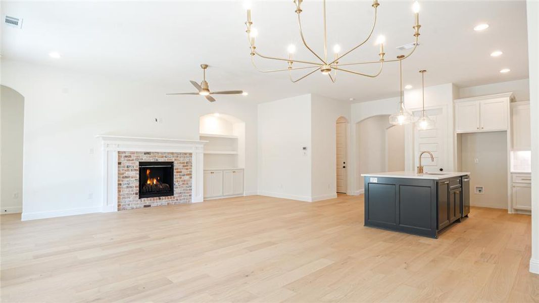 Kitchen featuring arched walkways, recessed lighting, open floor plan, light countertops, and a brick fireplace Kitchen featuring arched walkways, recessed lighting, open floor plan, light countertops, and a brick fireplace