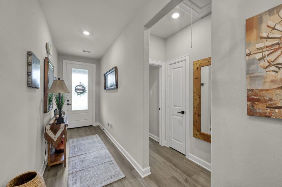 Wide entry hallway with durable wood-look flooring, neutral tones, recessed lighting, and a thoughtfully designed split floor plan that provides both privacy and an open, inviting flow throughout the home. Wide entry hallway with durable wood-look flooring, neutral tones, recessed lighting, and a thoughtfully designed split floor plan that provides both privacy and an open, inviting flow throughout the home.