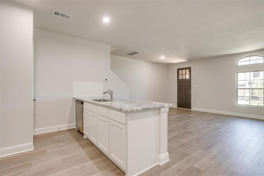 Kitchen with a peninsula, white cabinetry, light stone counters, light wood-type flooring, and recessed lighting Kitchen with a peninsula, white cabinetry, light stone counters, light wood-type flooring, and recessed lighting