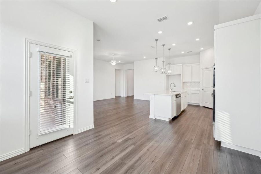 Kitchen with ceiling fan, dishwasher, pendant lighting, a center island with sink, and white cabinetry