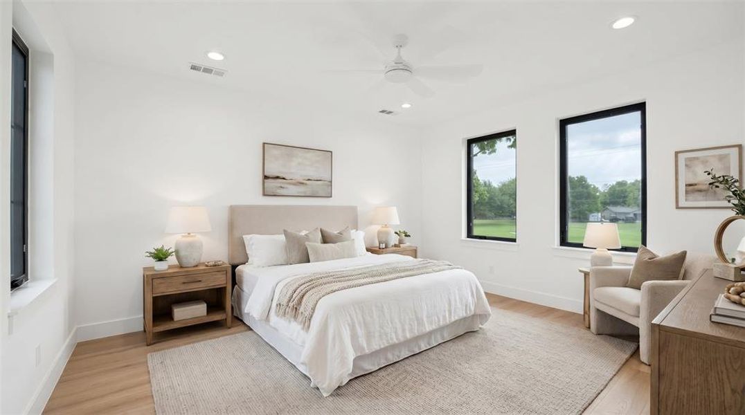 Spacious bedroom featuring light wood-finish flooring, white walls, and recessed lighting