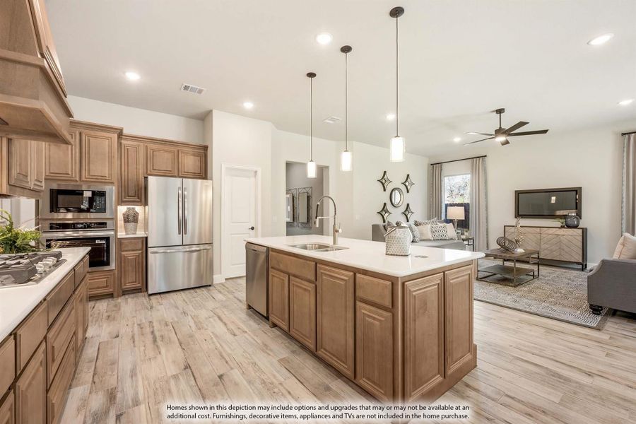 Open-concept kitchen with large center island, stainless steel appliances, wood cabinets, and adjoining living room with hardwood floors Open-concept kitchen with large center island, stainless steel appliances, wood cabinets, and adjoining living room with hardwood floors