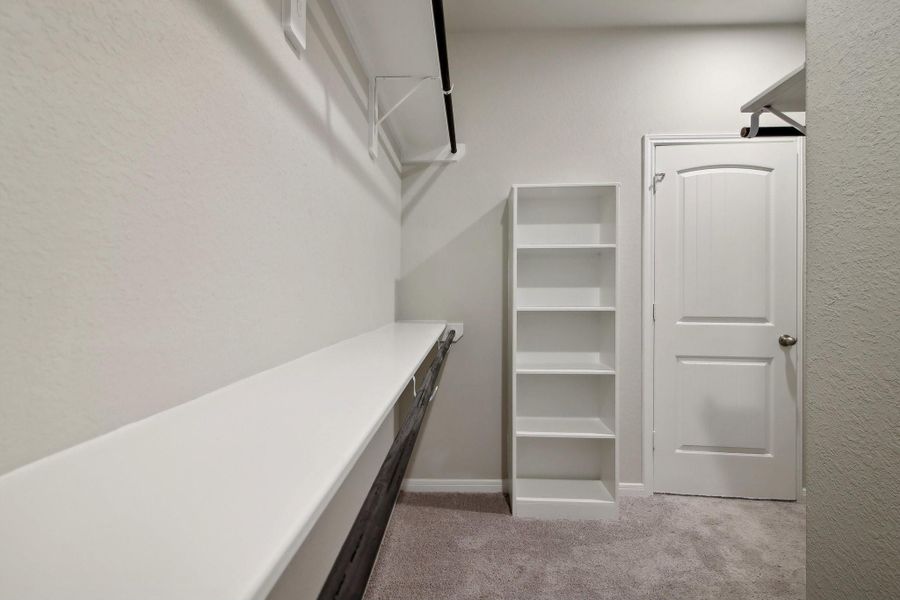 Discover this spacious primary closet that has built-in shelving that is perfect for your storage needs.