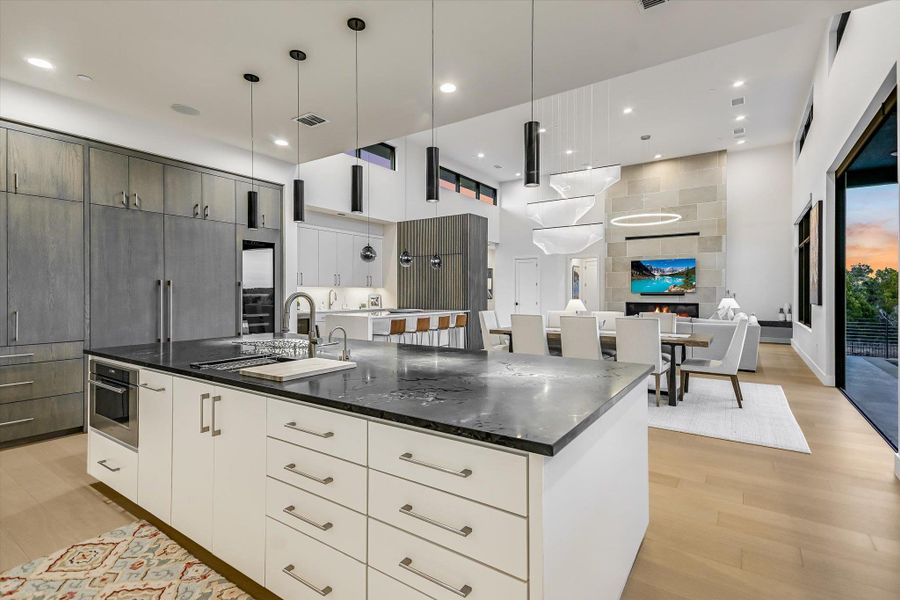 Dual tone kitchen with two tone cabinetry, modern cabinets, a spacious island, hanging light fixtures, and light wood-style floors Dual tone kitchen with two tone cabinetry, modern cabinets, a spacious island, hanging light fixtures, and light wood-style floors