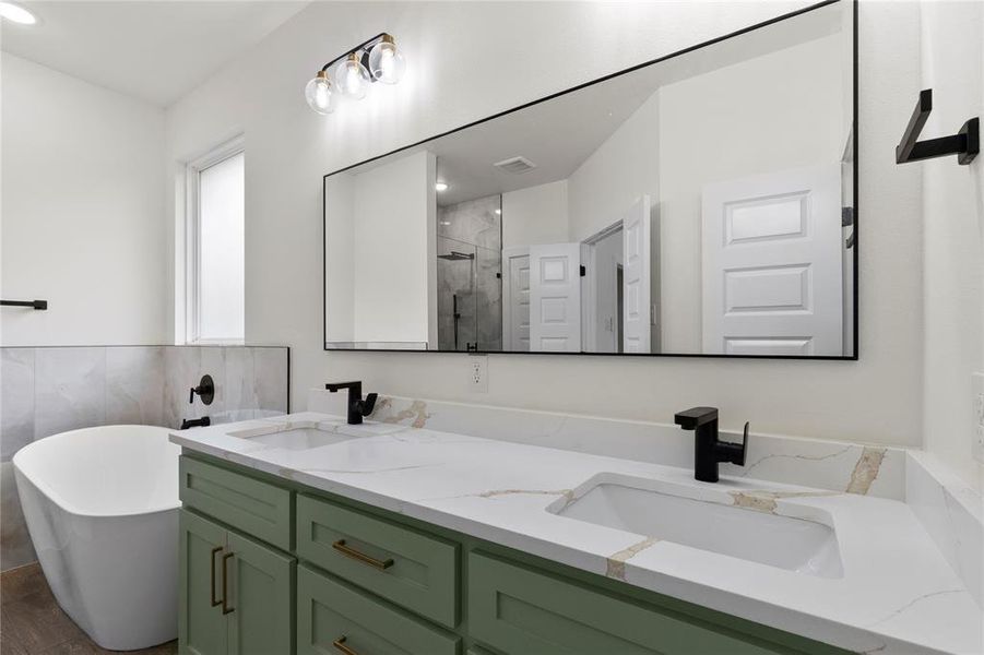 Double vanity featuring sage green cabinetry, integrated sinks, and a stone-finish countertop
