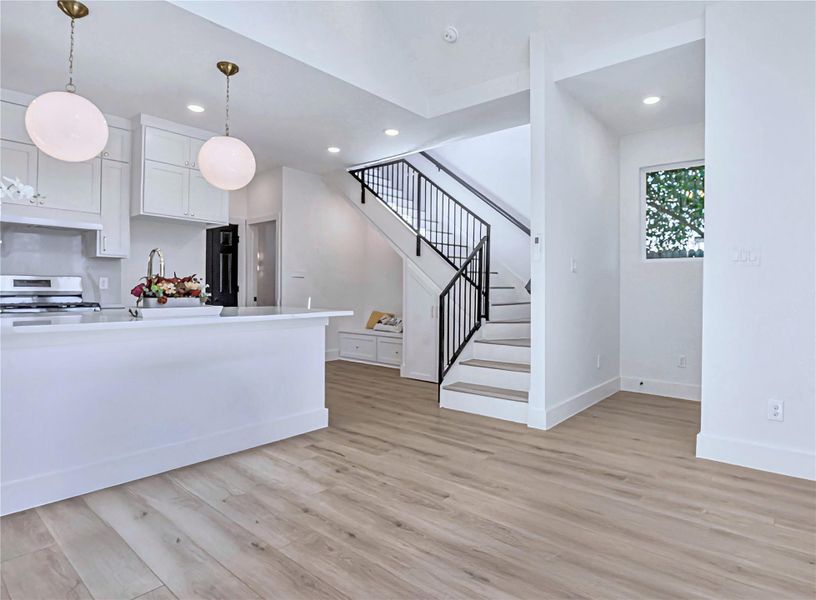 Kitchen featuring light wood finished floors, recessed lighting, hanging light fixtures, range, and under cabinet range hood