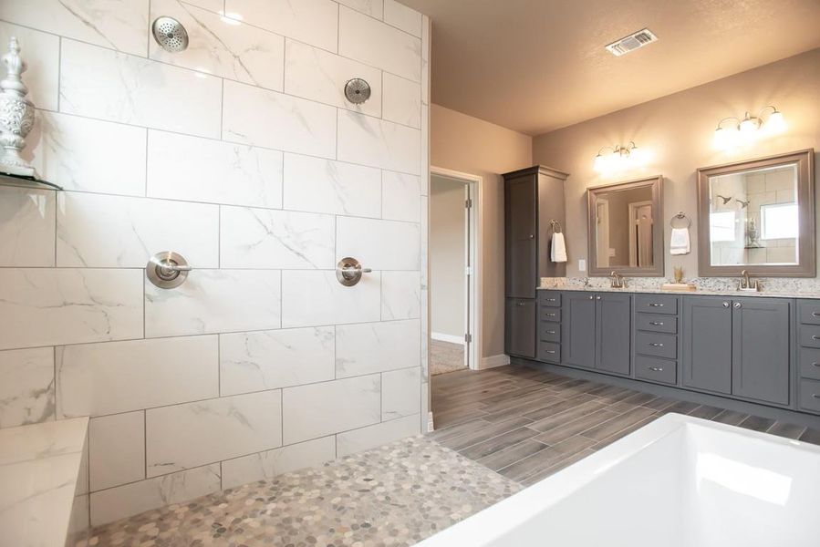 Bathroom with double vanity, walk in shower, and wood tiled floors Bathroom with double vanity, walk in shower, and wood tiled floors