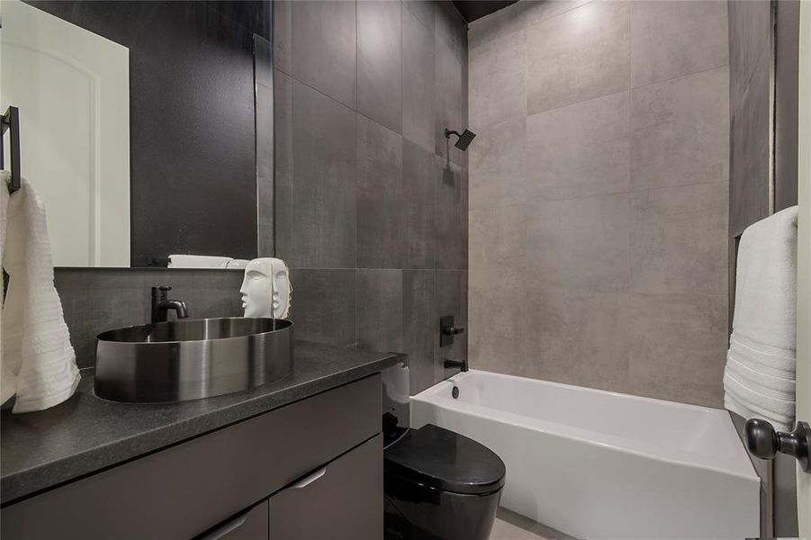 Bathroom featuring vanity, shower / bathtub combination, tile walls, and decorative backsplash Bathroom featuring vanity, shower / bathtub combination, tile walls, and decorative backsplash