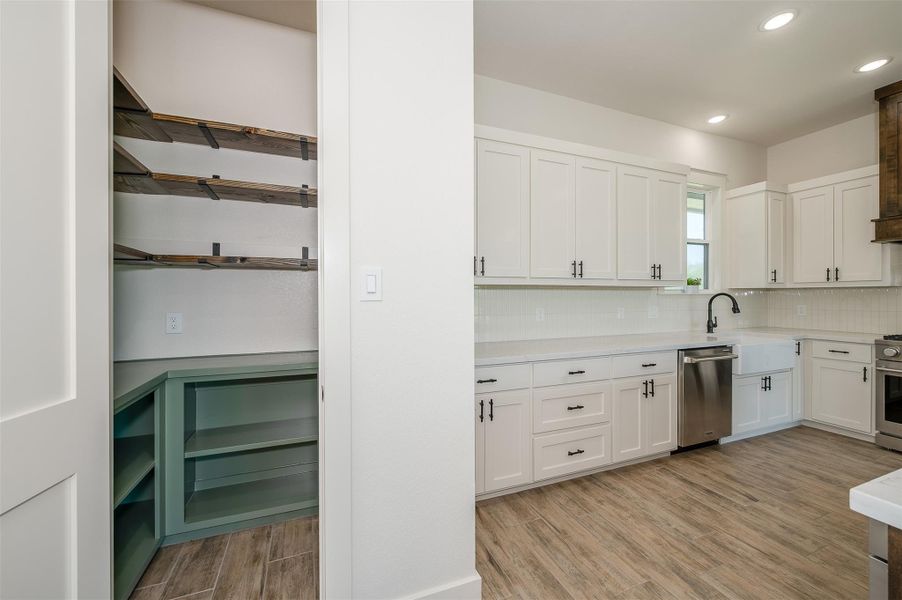 Kitchen featuring wood finish floors, white cabinetry, recessed lighting, tasteful backsplash, and appliances with stainless steel finishes