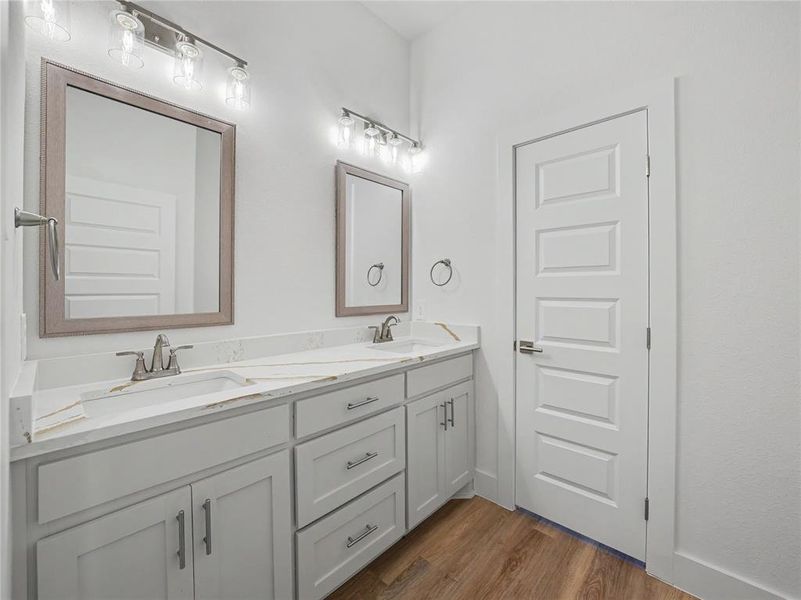 Dual vanity with light gray cabinetry, white countertops, and wood-finish flooring