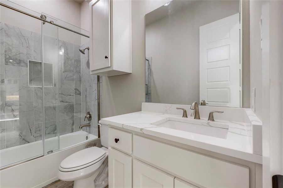 Full bathroom with toilet, enclosed tub / shower combo, and vanity