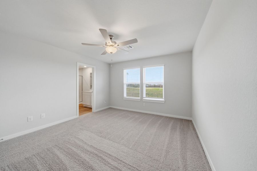 A room with a ceiling fan and a carpet.