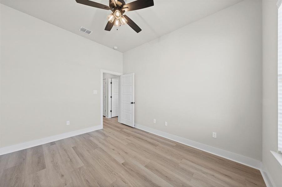 Empty room with light wood-type flooring, ceiling fan, and a high ceiling