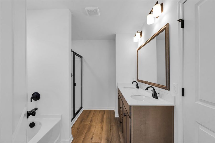 This bathroom features dual sinks and a shower, of