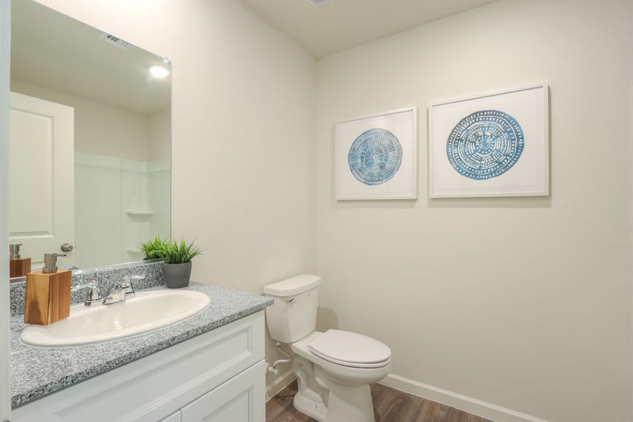 A bathroom with a sink toilet and a mirror.