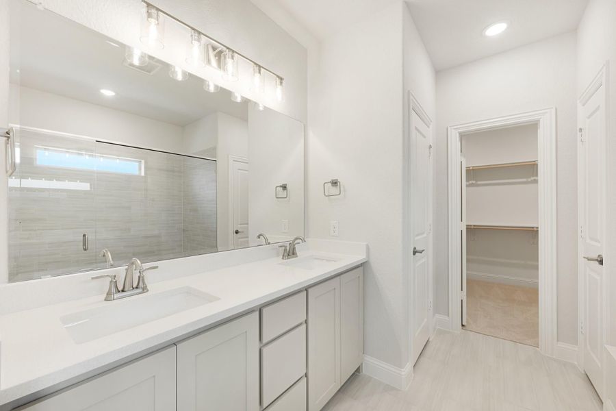 Bathroom with double sink vanity, large mirror, walk-in shower, and access to walk-in closet