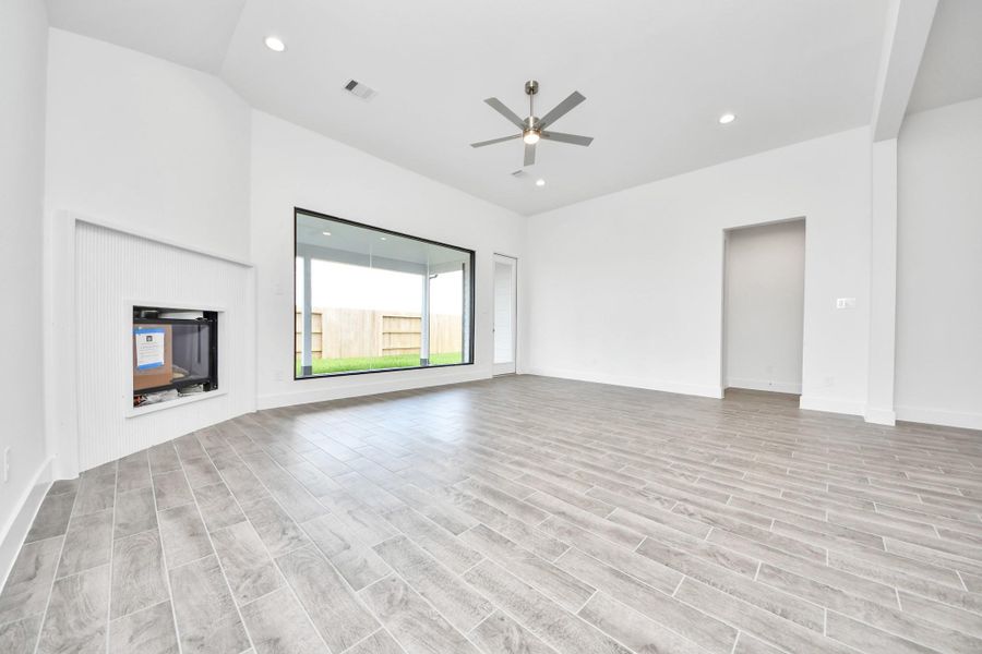 Welcome family and guests to your charming living room! With its high ceilings, recessed lighting, ceiling fan, custom paint, beautiful flooring, and large windows that let in abundant natural light, this room is perfect for gatherings.