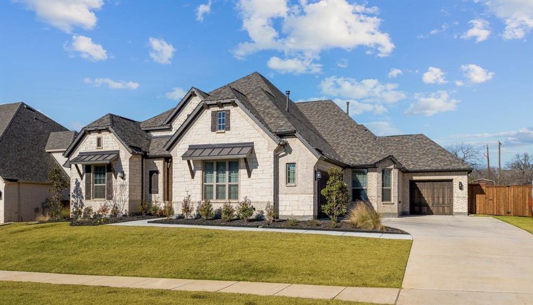 French country inspired facade with a garage and a front yard