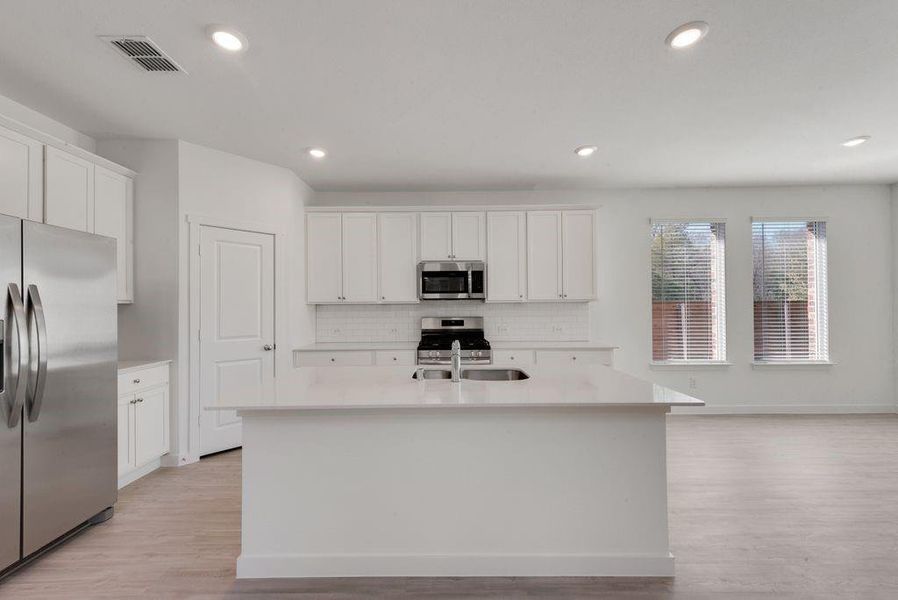 Kitchen with appliances with stainless steel finishes, decorative backsplash, light countertops, white cabinets, and recessed lighting Kitchen with appliances with stainless steel finishes, decorative backsplash, light countertops, white cabinets, and recessed lighting