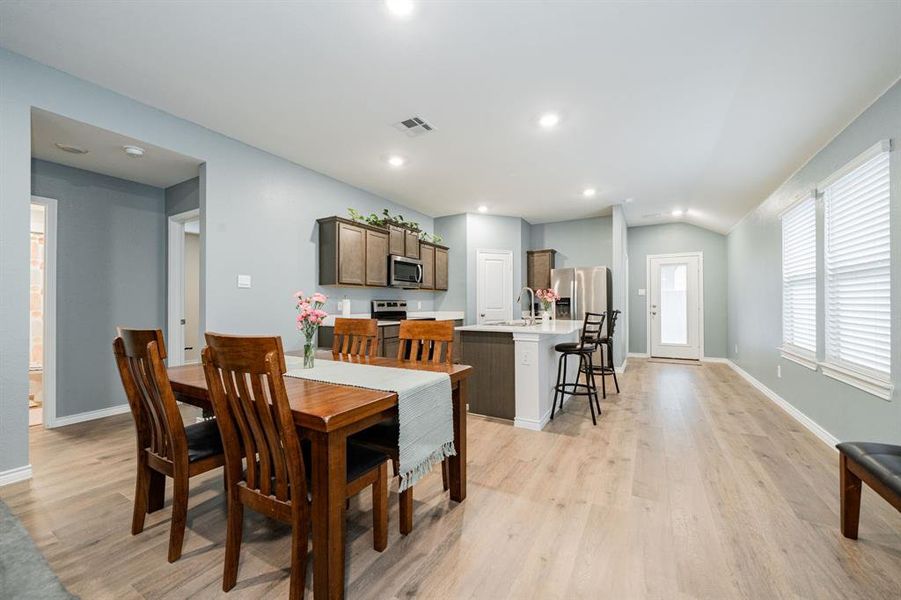 Dining area featuring light wood-style flooring, lofted ceiling, and recessed lighting Dining area featuring light wood-style flooring, lofted ceiling, and recessed lighting