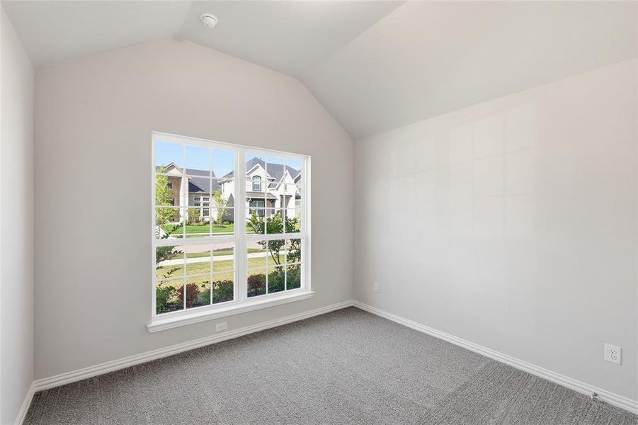Interior room featuring vaulted ceilings, neutral wall paint, and grey patterned carpeting