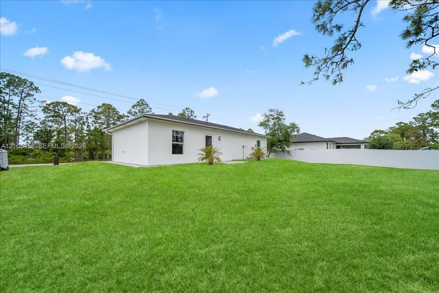 Expansive manicured lawn with mature landscaping and established trees, complemented by a modern white exterior featuring clean architectural lines and multiple windows Expansive manicured lawn with mature landscaping and established trees, complemented by a modern white exterior featuring clean architectural lines and multiple windows
