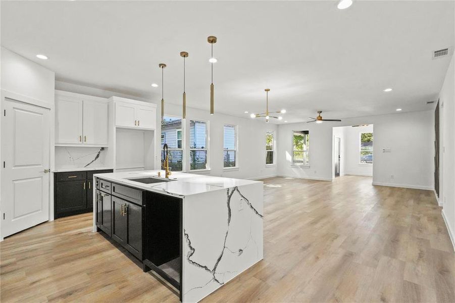 Kitchen featuring sink, hanging light fixtures, a kitchen island with sink, white cabinets, and ceiling fan with notable chandelier