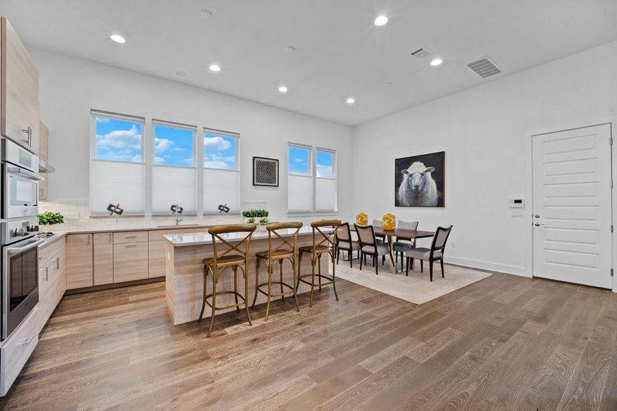 Kitchen with light brown cabinetry, a kitchen breakfast bar, a kitchen island, dark wood finished floors, and recessed lighting