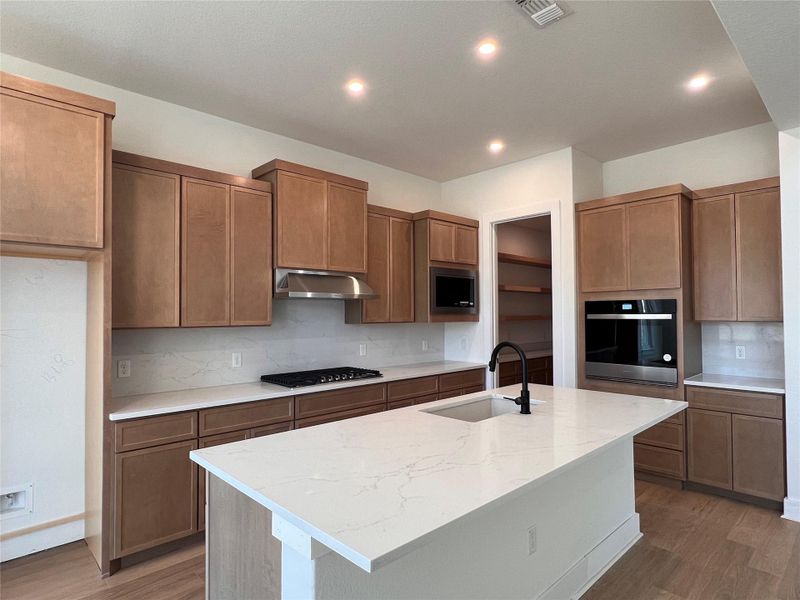 Kitchen featuring wood finish cabinets, tasteful backsplash, light stone countertops, and recessed lighting