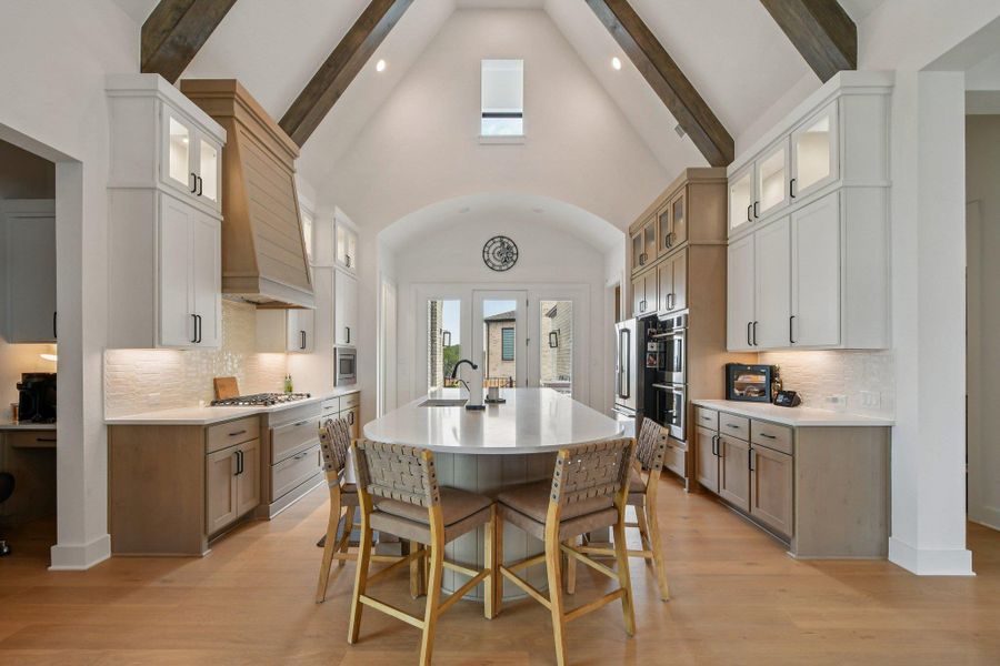 The kitchen features an expansive island with seating, a gas range with a decorative wood hood, and a double oven The kitchen features an expansive island with seating, a gas range with a decorative wood hood, and a double oven