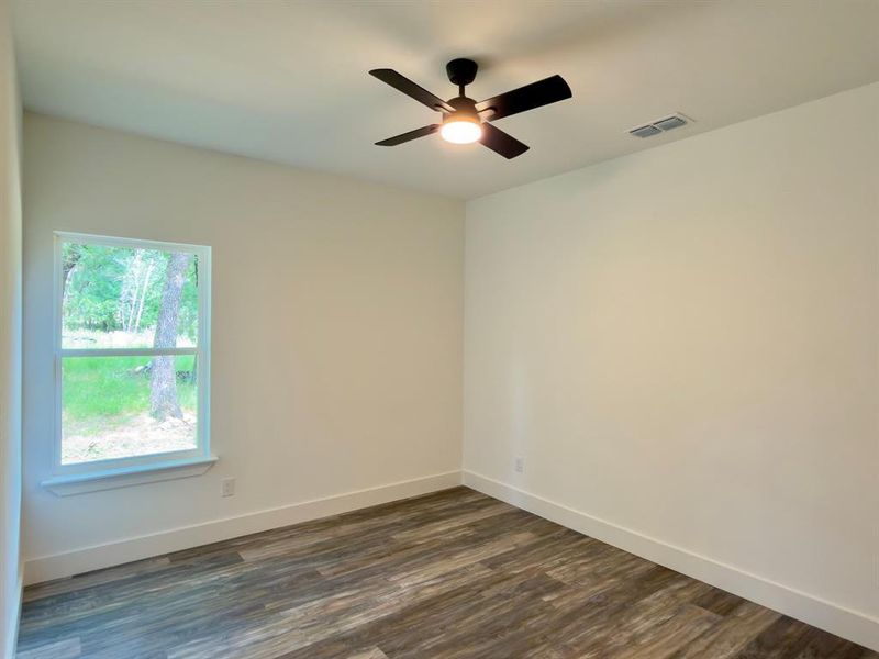 Room featuring wood-finish flooring, a contemporary ceiling fan with integrated lighting, and a white-trimmed window