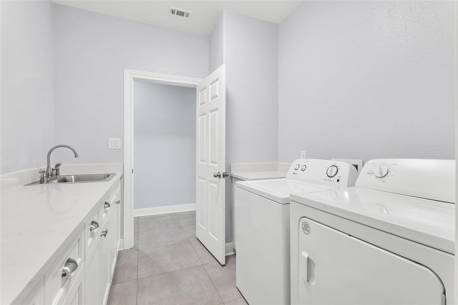Laundry room with washing machine and clothes dryer, light tile patterned flooring, and cabinet space