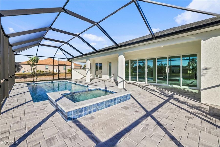 View of swimming pool featuring a sunroom, a patio area, a pool with connected hot tub, and glass enclosure