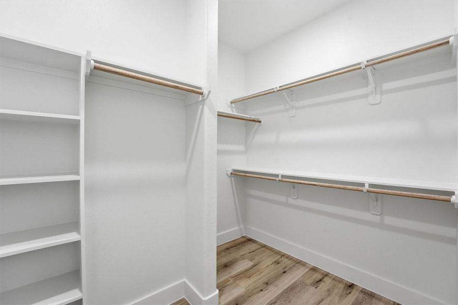 Large walk-in closet in primary suite with built-in shelving.
