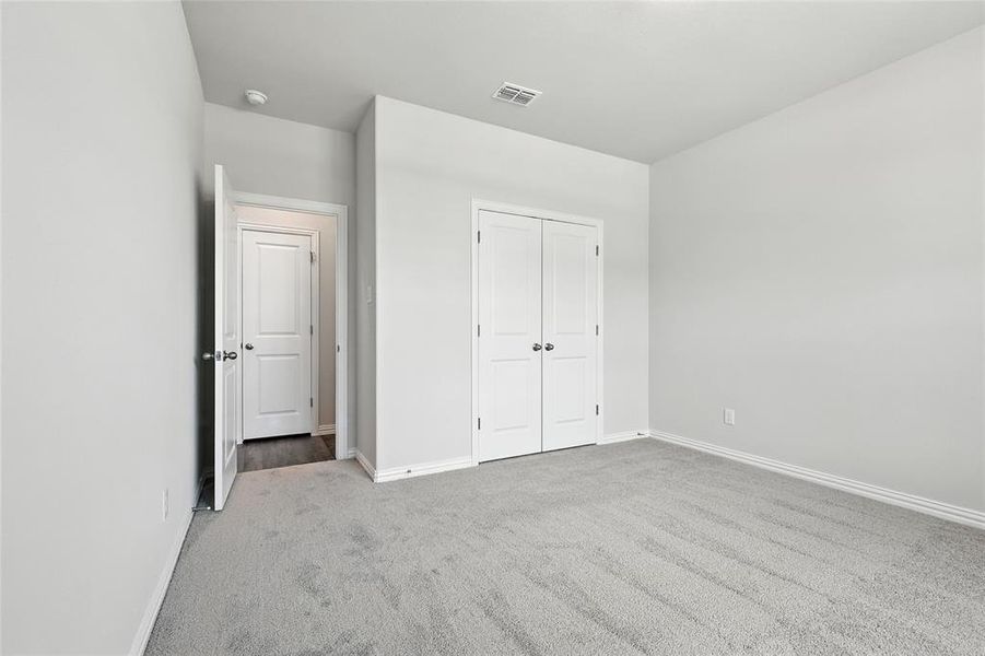 Unfurnished bedroom with light colored carpet and a closet
