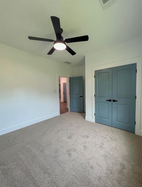 Unfurnished bedroom with carpet, ceiling fan, and a closet